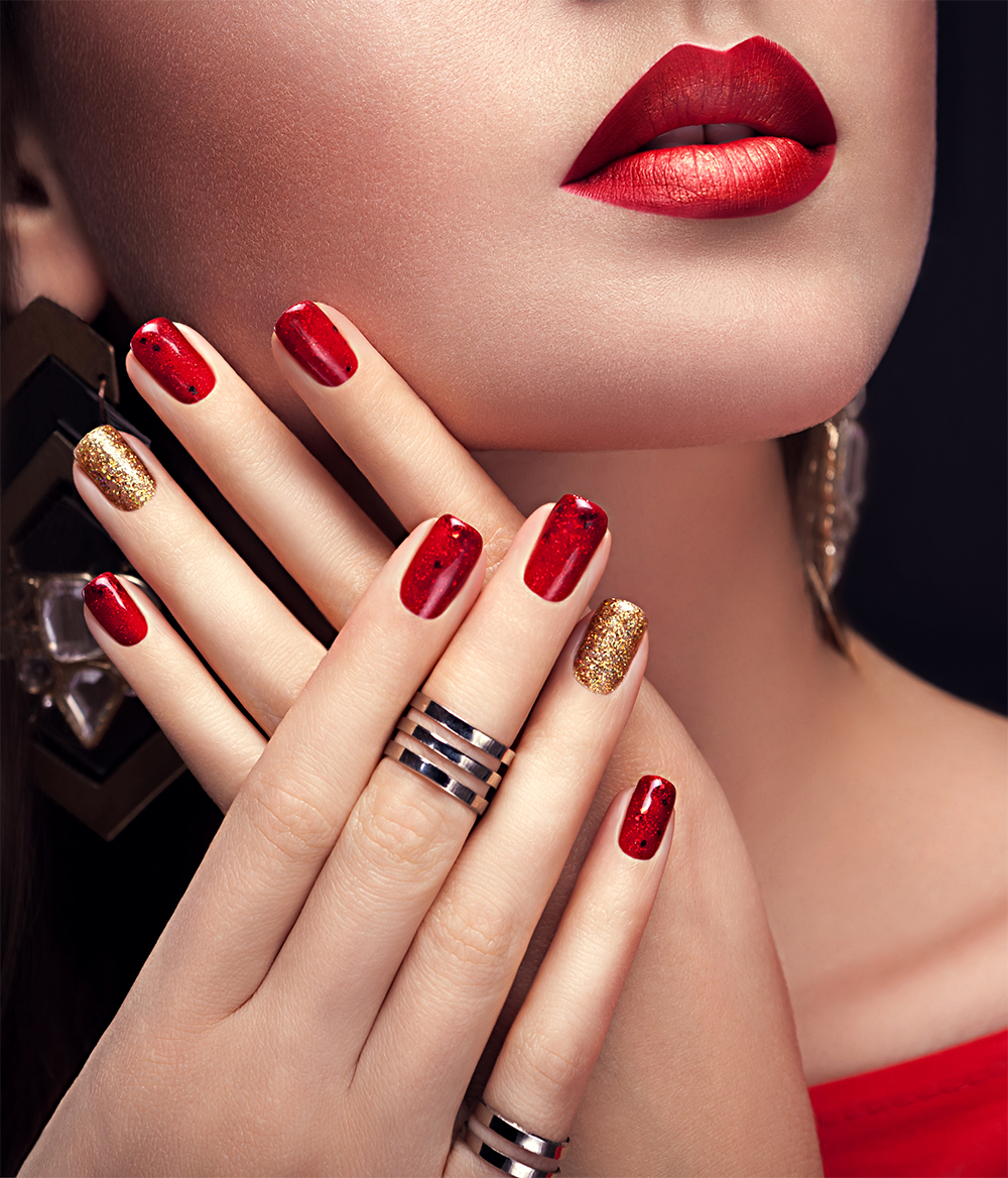 Beautiful woman with perfect make-up and red and golden manicure wearing jewellery